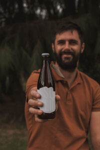 Man holding out craft beer with white label.